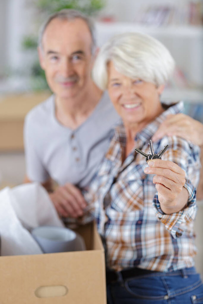 senior couple showing house keys light effect - Foto, imagen