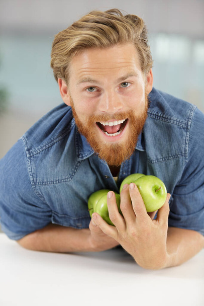 man trying not to drop apples held against himself - Foto, afbeelding