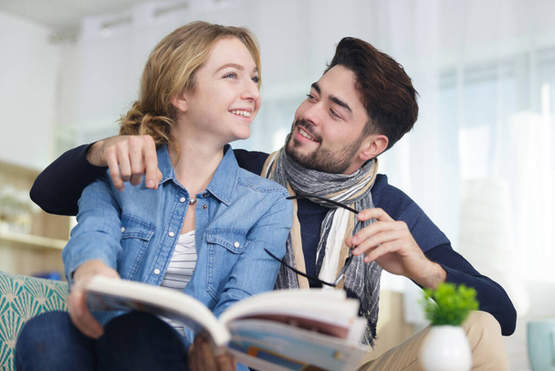 joven pareja mirando a través de un libro y riendo
 - Foto, Imagen