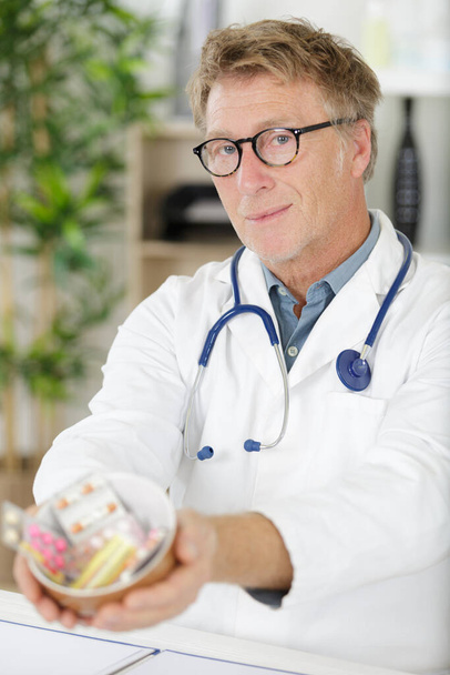 portrait of senior doctor offering bunch of pills - Photo, Image