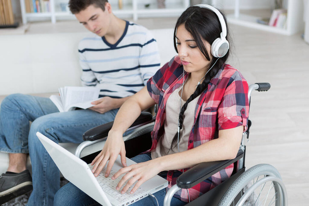 young boy reading book young lady in wheelchair using laptop - Foto, imagen
