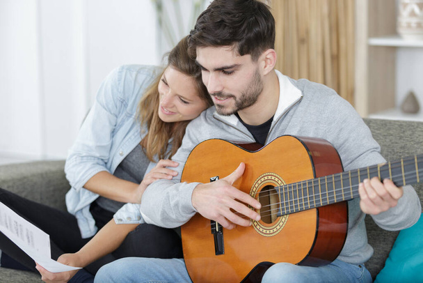 loving couple with guitar in the room at home - Fotó, kép