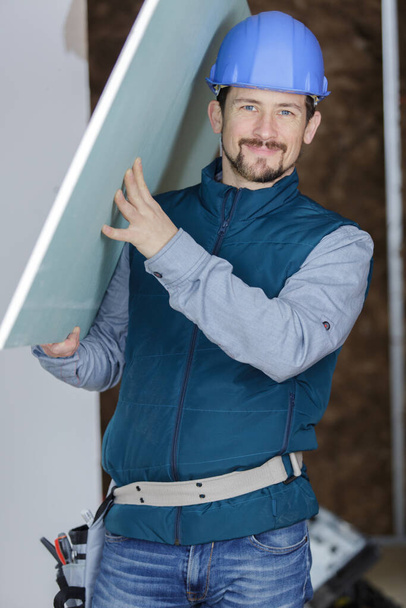 portrait of tradesman carrying plasterboard - Photo, Image