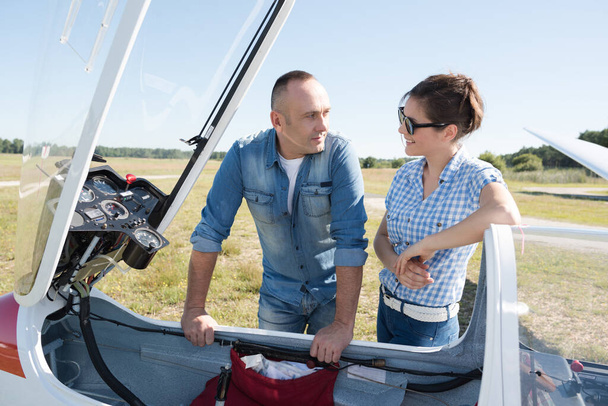 couple standing by a sailplane at an airfield - Photo, image