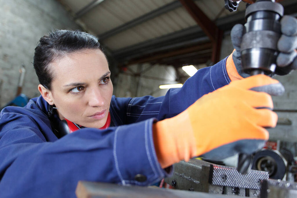 female apprentice using drill in factory - Photo, Image