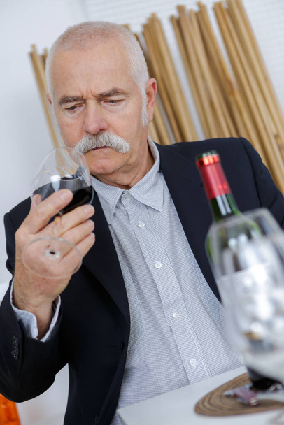 senior man examining glass of red wine - Zdjęcie, obraz