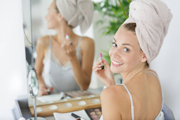 woman sat at bathroom mirror putting on her makeup - Zdjęcie, obraz