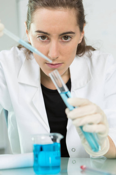 young woman holding glass lab tube with a blue liquid - Foto, Imagen