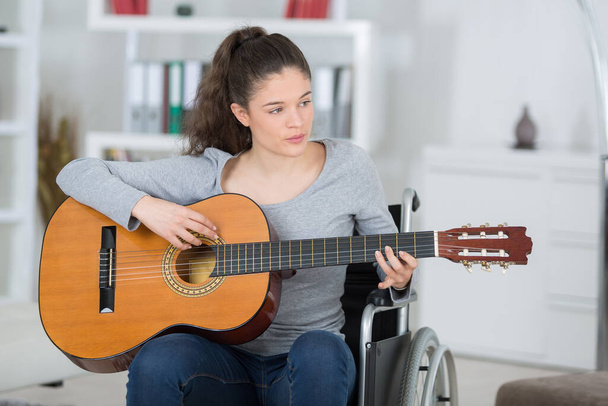 young woman on the wheelchair playing the guitar - Φωτογραφία, εικόνα