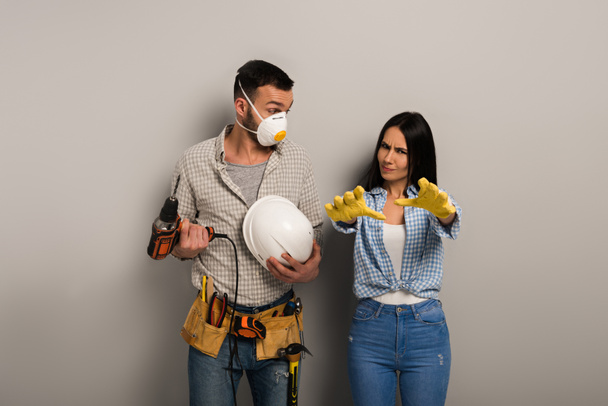 trabajadores manuales emocionales en máscara de seguridad con taladro eléctrico y casco en gris
  - Foto, Imagen