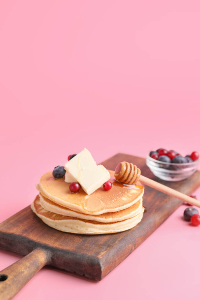 Leckere Pfannkuchen mit Honig, Butter und Beeren auf farbigem Hintergrund - Foto, Bild