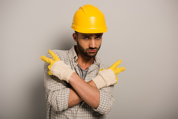 Ouvrier condescendant en casque jaune et gants gesticulant sur gris
  - Photo, image