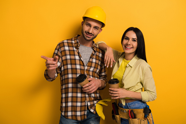 professional manual workers with coffee to go pointing on yellow      - Foto, Imagem