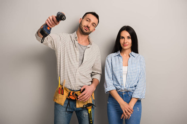 happy manual workers holding electric drill on grey  - Photo, Image