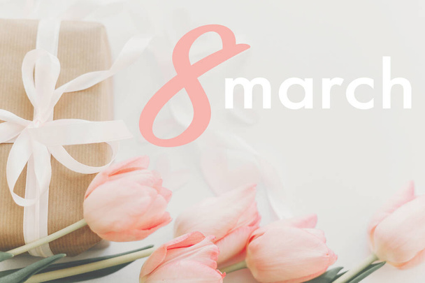 8. März. Glückliche Glückwunschkarte zum Frauentag. 8. März Text auf rosa Tulpen und Geschenkbox mit Band auf weißem Hintergrund. Stilvolles zartes Bild. Handschriftlicher Text, Schriftzug - Foto, Bild