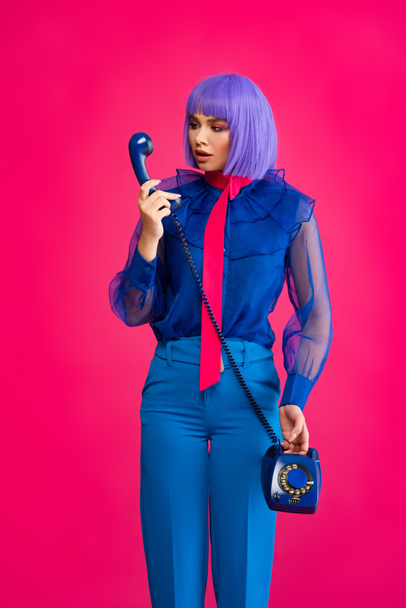 divatos lány lila parókában beszél retro telefonon, elszigetelt rózsaszín - Fotó, kép