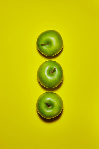 Groene appel op gele achtergrond. Platte lay, bovenaanzicht, kopieerruimte. Voedselvoedingsconcept. - Foto, afbeelding