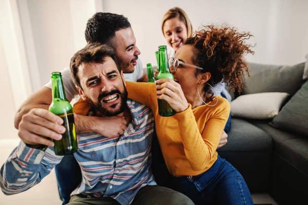 Group of cheerful friends sitting at home and watching football game on television. Their favorite team is winning. - 写真・画像