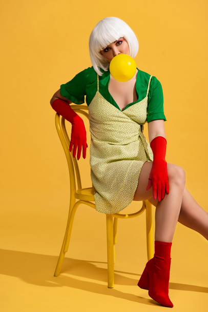 pop art woman in white wig with bubble gum sitting on chair - Fotó, kép