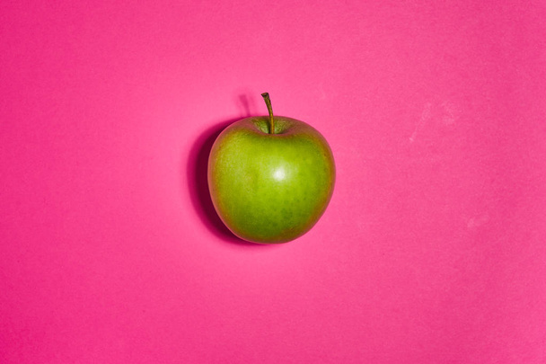 Zielone jabłko na różowym tle. Płaskie ułożenie, widok z góry, przestrzeń kopiowania. Koncepcja żywienia. - Zdjęcie, obraz
