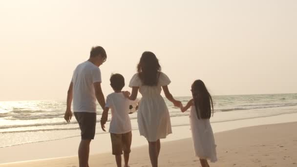 Aziatische jonge gelukkige familie genieten van vakantie op het strand in de avond. Pap, mam en kind ontspannen samen in de buurt van de zee als de zon ondergaat. Lifestyle reisvakantie zomervakantie concept. 4k slow motion. - Video