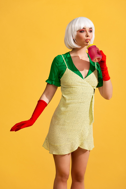hermosa chica de arte pop en vestido amarillo y peluca blanca beber bebida fresca del frasco, aislado en amarillo
 - Foto, Imagen