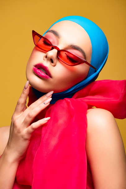 beautiful fashionable girl in trendy scarf and red sunglasses with closed eyes, isolated on yellow - Foto, Imagen