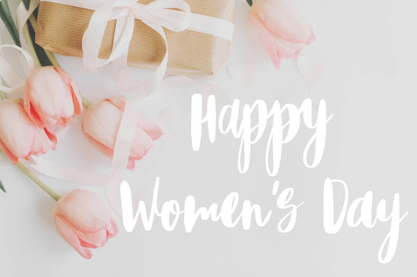 Счастливого женского дня. Happy women 's day text on pink tulips with gift box on white background. Стильный нежный образ. Письменность от руки. Международный женский день, 8 марта
 - Фото, изображение