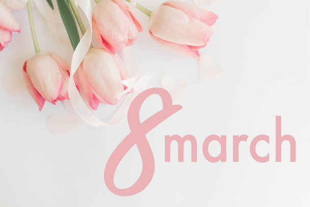 8 marzo. Buon biglietto di auguri per il giorno delle donne. 8 marzo testo su tulipani rosa con nastro su sfondo bianco, posa piatta. Elegante immagine tenera. Lettere scritte a mano. Giornata internazionale della donna
 - Foto, immagini