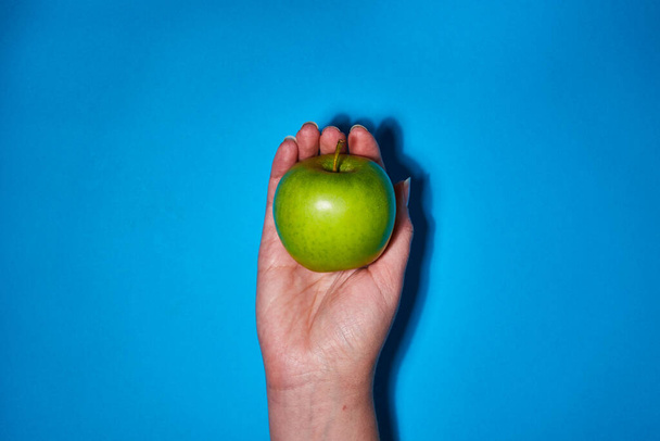 Lemon in hand on blue background. Flat lay, top view, copy space . Food dietary concept. - Фото, зображення