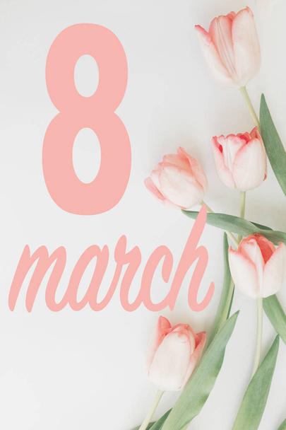 8 marzo. Felice giorno delle donne biglietto di auguri floreale. 8 marzo testo su tulipani rosa elegante bordo piatto giaceva su sfondo bianco. Lettere scritte a mano. Giornata internazionale della donna. Immagine verticale
 - Foto, immagini