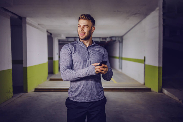 Young smiling muscular man using smart phone. - Foto, Bild