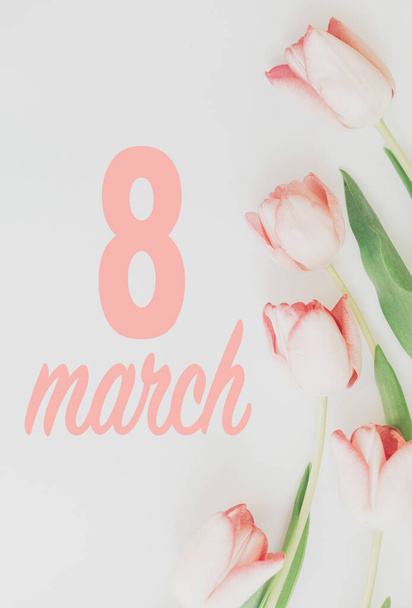Március 8. Boldog nők napi virágüdvözlő kártya. 8 március szöveget rózsaszín tulipán elegáns határ lapos feküdt fehér háttér. Kézzel írott betűk. Nemzetközi nőnap. Függőleges kép - Fotó, kép
