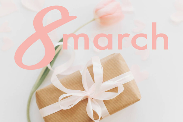 8. März. Glückliche Glückwunschkarte zum Frauentag. 8. März Text auf rosa Tulpe mit Geschenkbox auf weißem Hintergrund, flach gelegt. Stilvolles zartes Bild. Handschriftlicher Schriftzug. Internationaler Frauentag - Foto, Bild