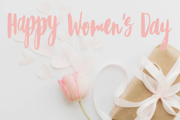 Glücklicher Frauentag. Happy Women 's Day Text auf rosa Tulpe mit Geschenkbox auf weißem Hintergrund. Stilvolles zartes Bild. Handschriftlicher Schriftzug. Internationaler Frauentag, 8. März - Foto, Bild