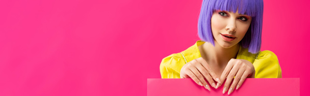 πανοραμική φωτογραφία του κοριτσιού pop art σε μωβ περούκα κρατώντας κενό πλακάτ, απομονώνονται σε ροζ - Φωτογραφία, εικόνα
