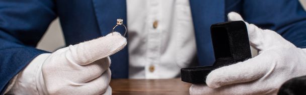 Vista recortada del anillo de sujeción del tasador de joyas con gemas y caja sobre mesa aislada en gris, plano panorámico
 - Foto, Imagen