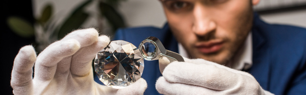 Foco seletivo de avaliador de jóias examinando pedra preciosa com lupa, tiro panorâmico
 - Foto, Imagem