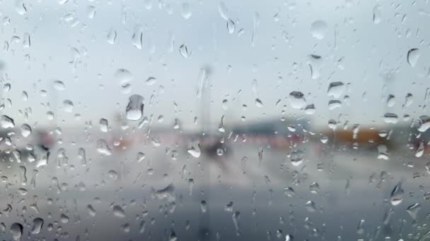 Closeup 4k video přes okno letadla pokryté kapkami vody na letištním terminálu v dešti bouře - Záběry, video