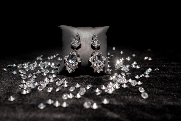 Foco seletivo de ganhos de jóias perto de pedras preciosas em veludo preto isolado em preto
  - Foto, Imagem