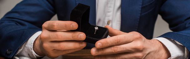 Przycięty widok rzeczoznawcy biżuterii pudełko z biżuterią pierścień przy stole odizolowany na szarym, panoramicznym ujęciu - Zdjęcie, obraz