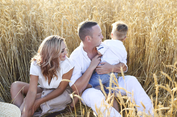 Gelukkige familie met gelukkige zoon in de zomer zonsondergang veld. Geluk en liefde concept - Foto, afbeelding