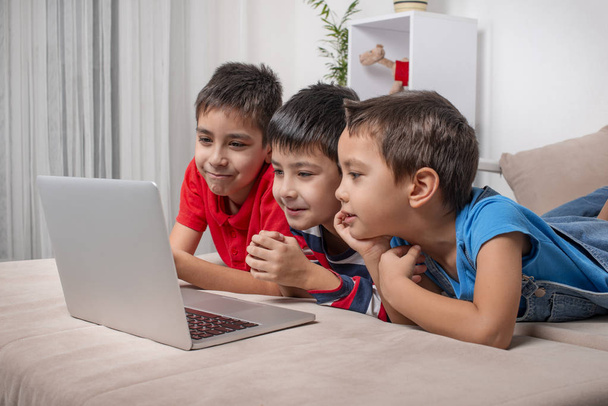 Três irmãos ou amigos divertidos navegando juntos no internrt em um laptop. Estilo de vida moderno
.   - Foto, Imagem