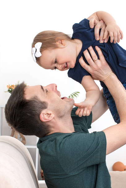 Een jonge man met een dochtertje brengt tijd thuis door. De moderne rol van mannen in het gezin. - Foto, afbeelding