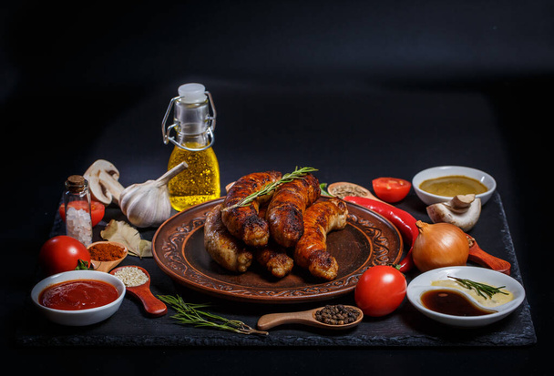 Grilled sausages, vegetables, hot peppers and various spices and ingredients on a black background - Foto, immagini