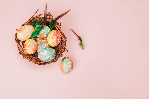 Coloeful huevos de Pascua en el nido sobre fondo de color rosa pastel
. - Foto, Imagen