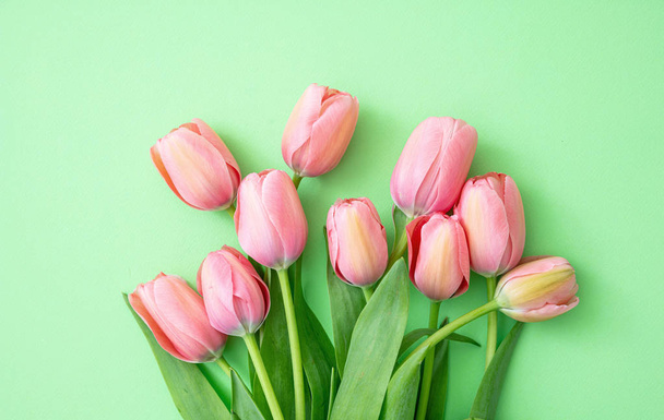 Springtime, easter. Pink tulips bouquet on green background, top view. Women day or mothers day greeting card template - Foto, Bild