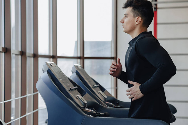 stylish guy in the gym is training on the treadmill. Healthy Lifestyle. wellness. - Photo, Image