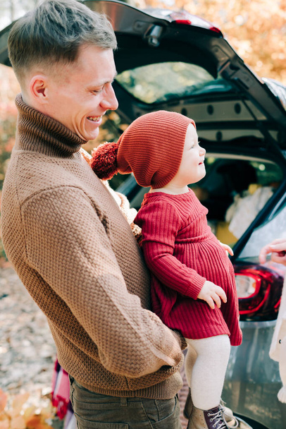 happy dad and daughter stand near the open trunk of a car in a pine forest - Photo, Image