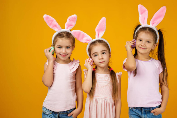 child girls holding painted Easter eggs - Fotó, kép